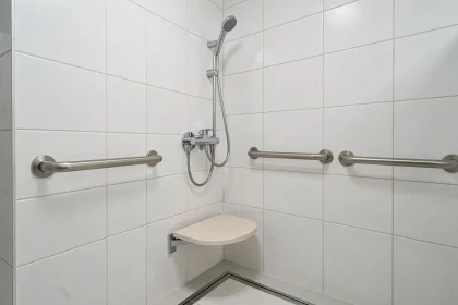 Mitigeur thermostatique douche installé à hauteur PMR avec barre d'appui et siège rabattable dans une salle de bains accessible